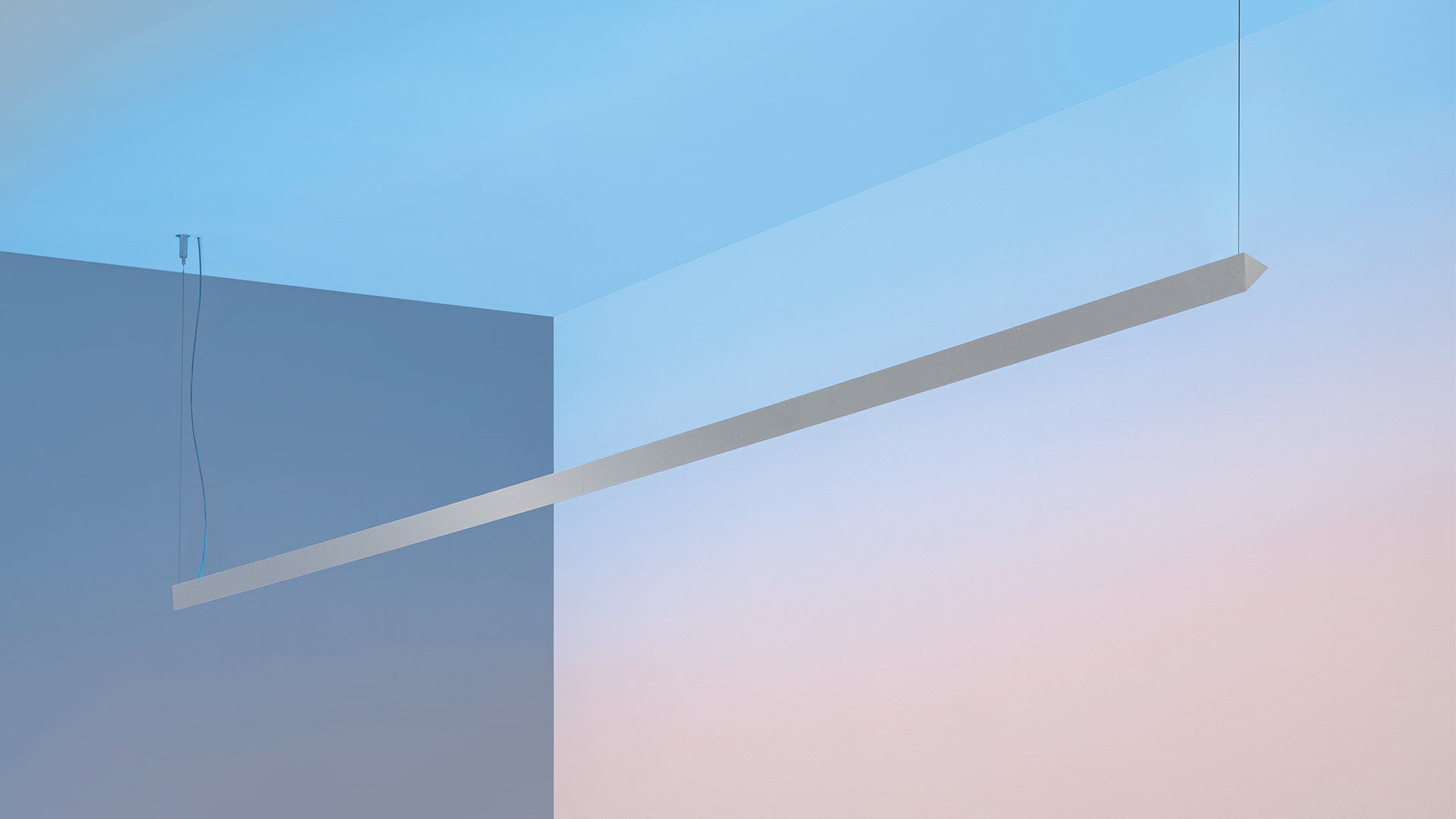 Artemide Dusk pendant lamp: slim elongated white linear fixture suspended diagonally by cables in a minimalist interior