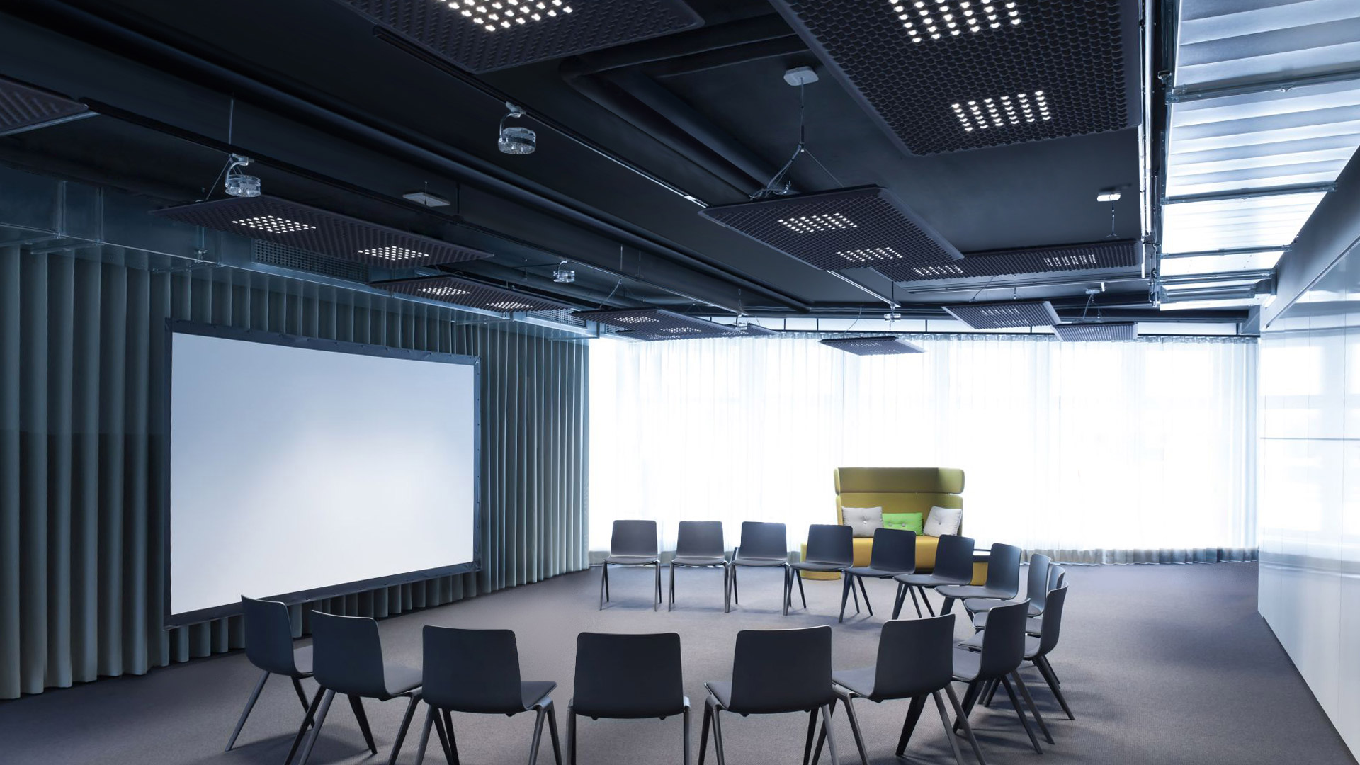 Modern conference room with Artemide Eggboard and Eggboard Matrix ceiling lights, dark decor, presentation screen, and circular seating arrangement