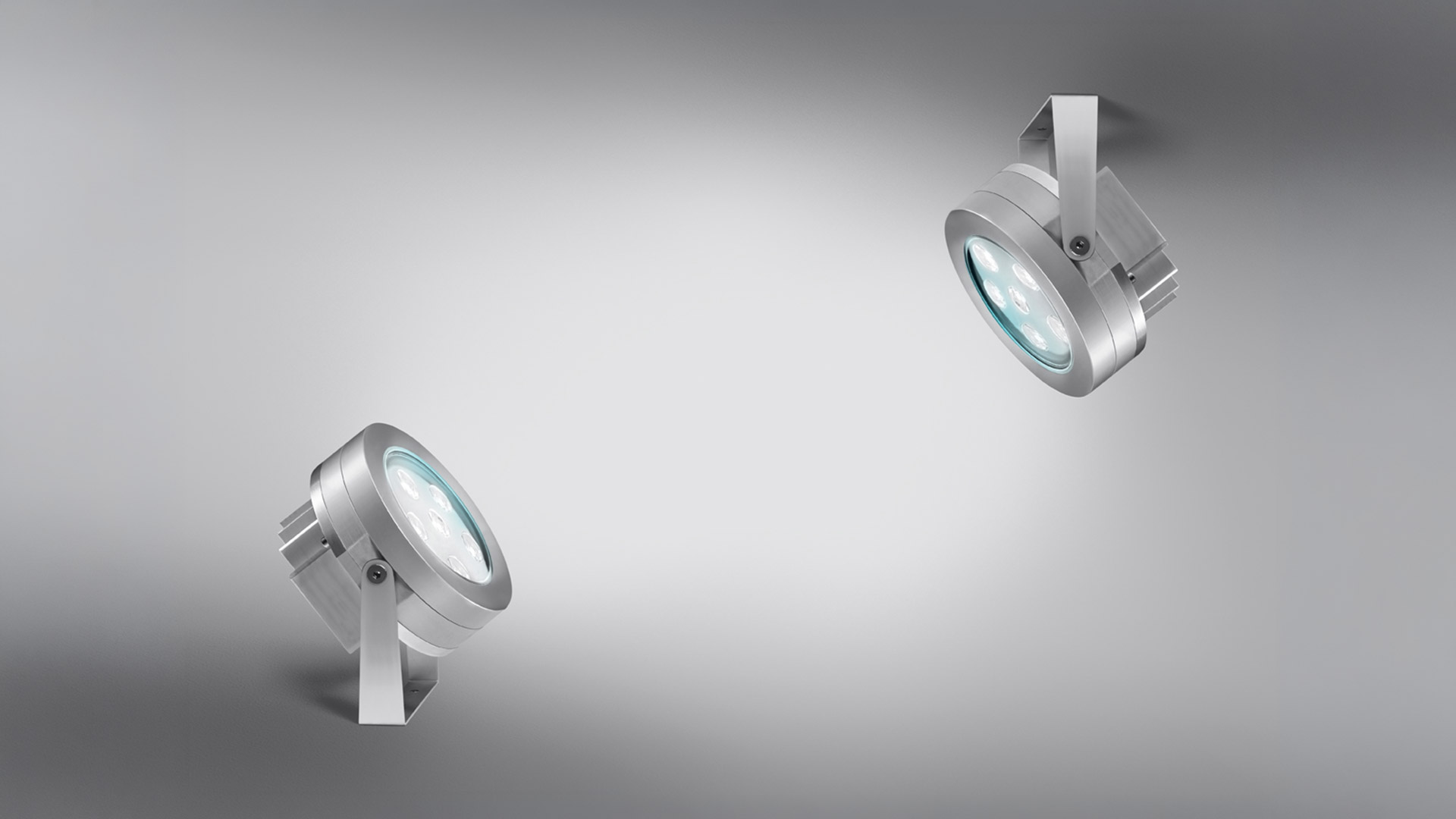 Two Artemide Ego Spot outdoor spotlights in brushed aluminum, with circular LED lens, mounted on adjustable brackets