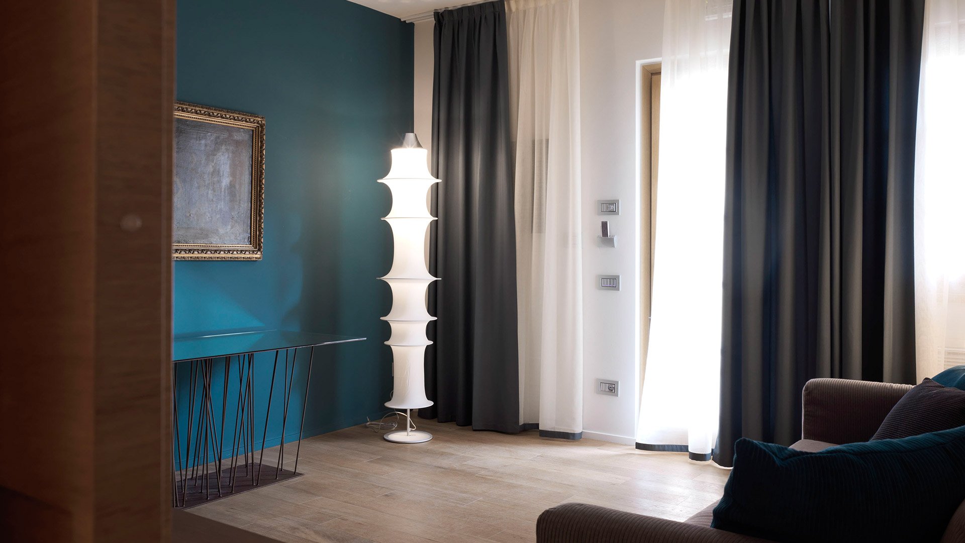 Artemide Falkland Terra floor lamp with stacked oval diffusers in a modern living room with teal accent wall and gray curtains