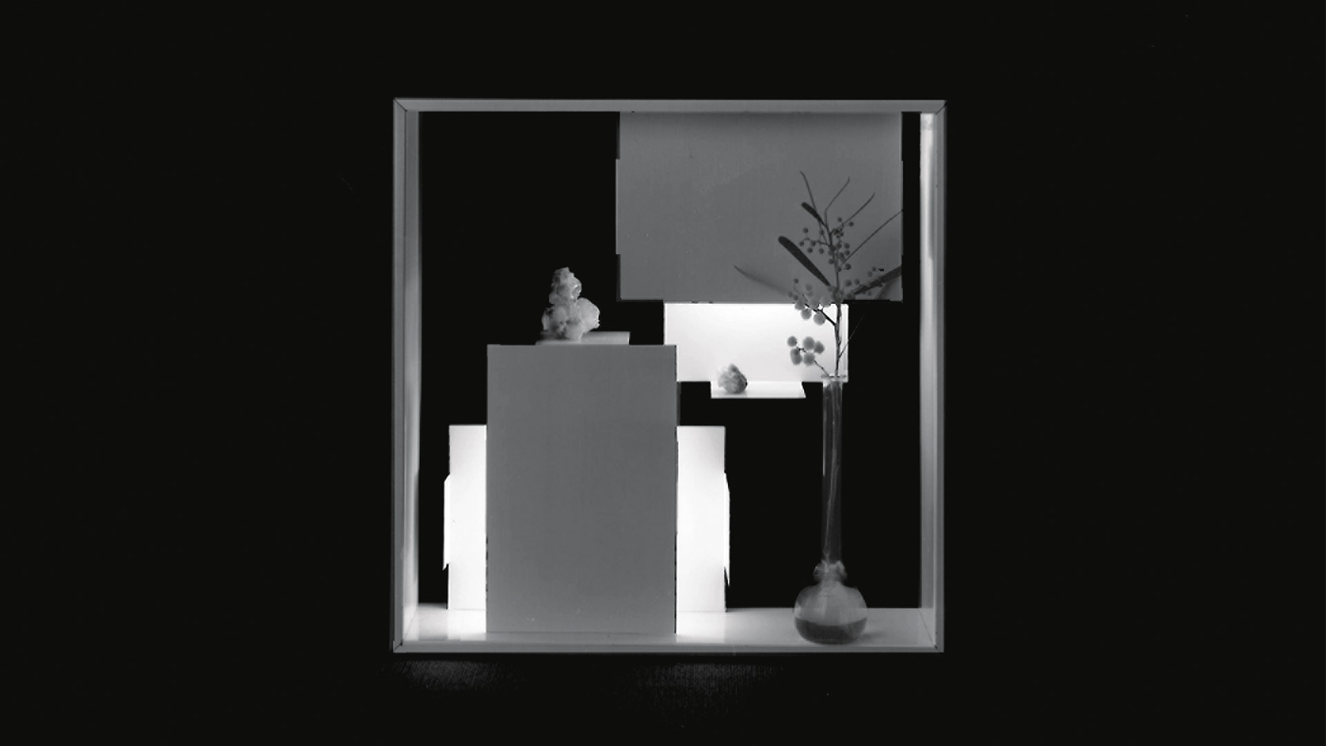 Artemide Fato wall lamp, square golden box with geometric inner panels casting warm light, mounted on a white wall near a window