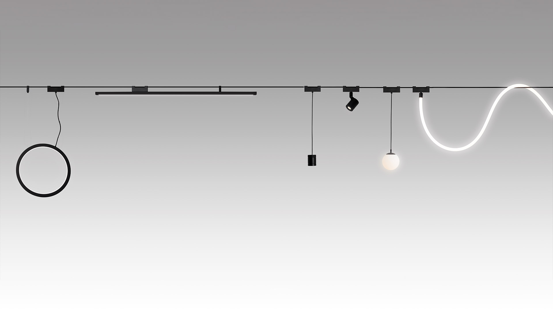 Artemide Funivia Outdoor black track spotlight mounted on cable system, directed downward, illuminating foliage below