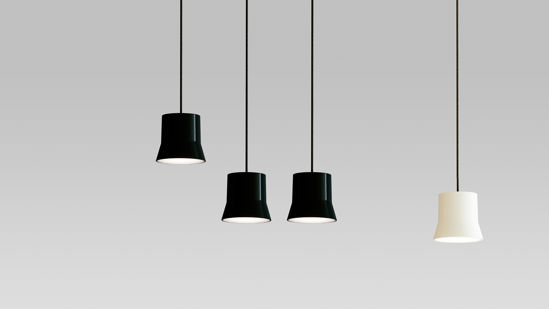 Four Artemide Giò Light pendant lamps hanging at varying heights: three black and one white, with truncated cone shades on thin black cords