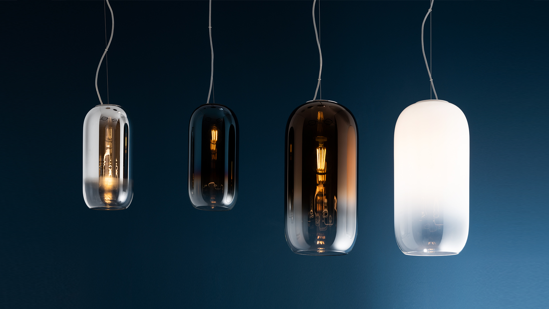 Multiple Artemide Gople pendant lamps glowing in pink, purple, and blue hues, suspended among lush tropical foliage in a dark setting