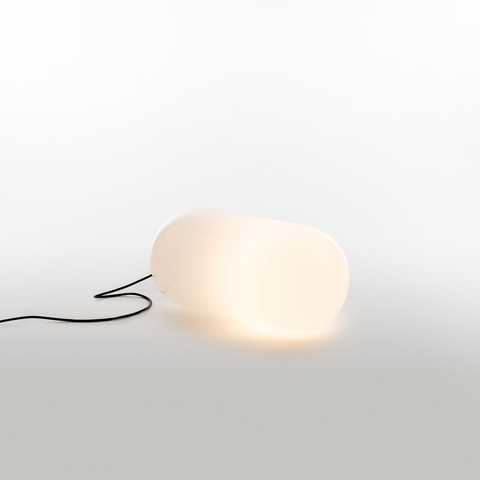 Artemide Gople Outdoor floor lamp: organic pebble-shaped white opal diffuser emitting warm light, with black power cord