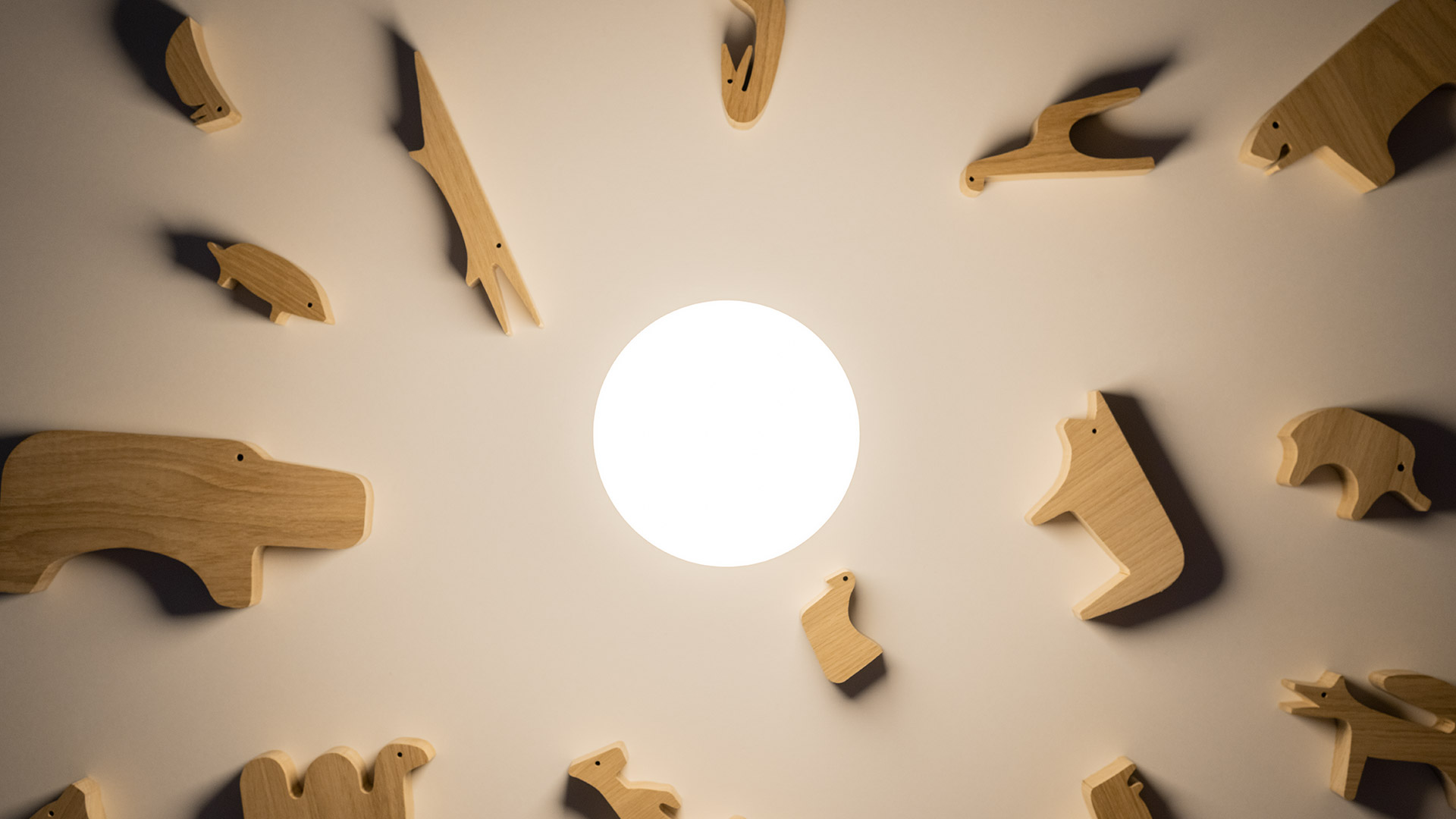 Artemide Gople Portable lamp, glowing white capsule shape, on a dark side table beside a red Y-shaped coat stand, yellow background