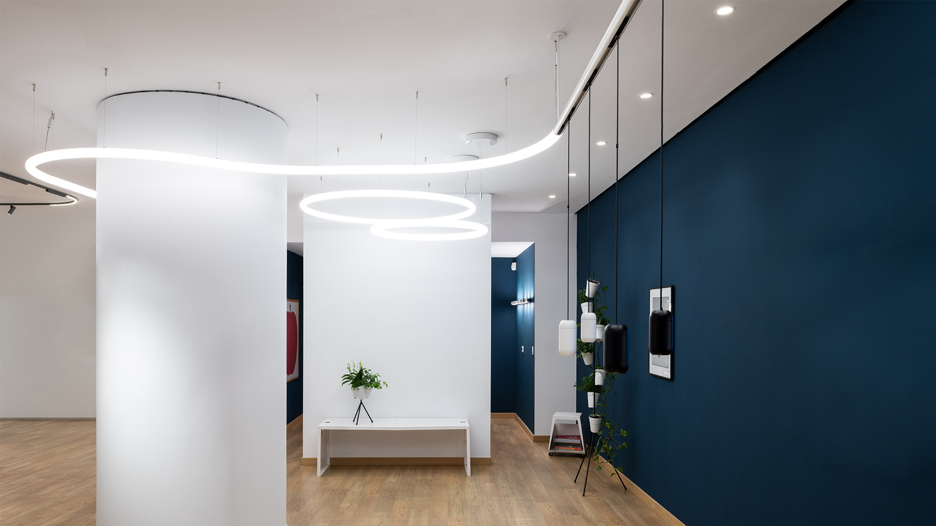 Artemide Gople System: white pendant and two adjustable spotlights on a ceiling track above a minimalist desk workspace