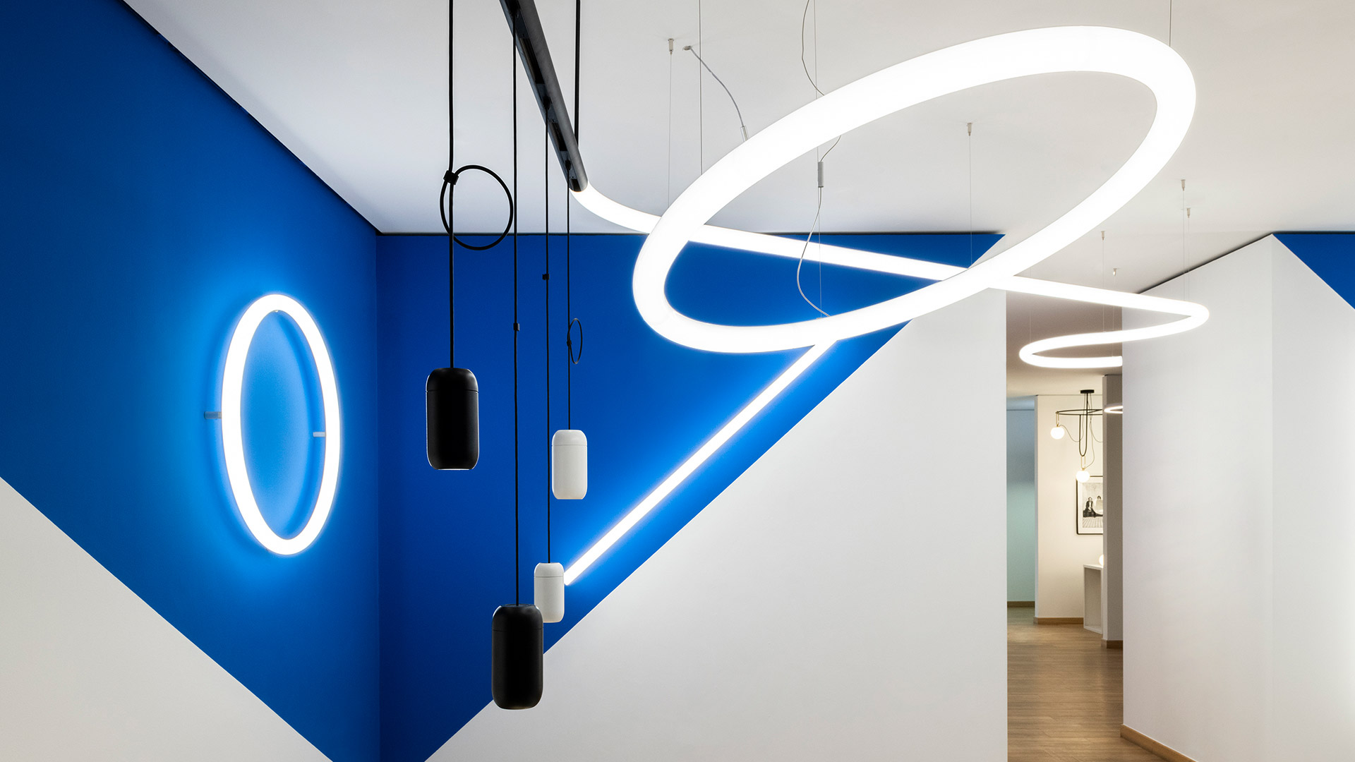 Artemide Gople System: three white cylindrical track spotlights and two white capsule pendant lights hanging from a black rail