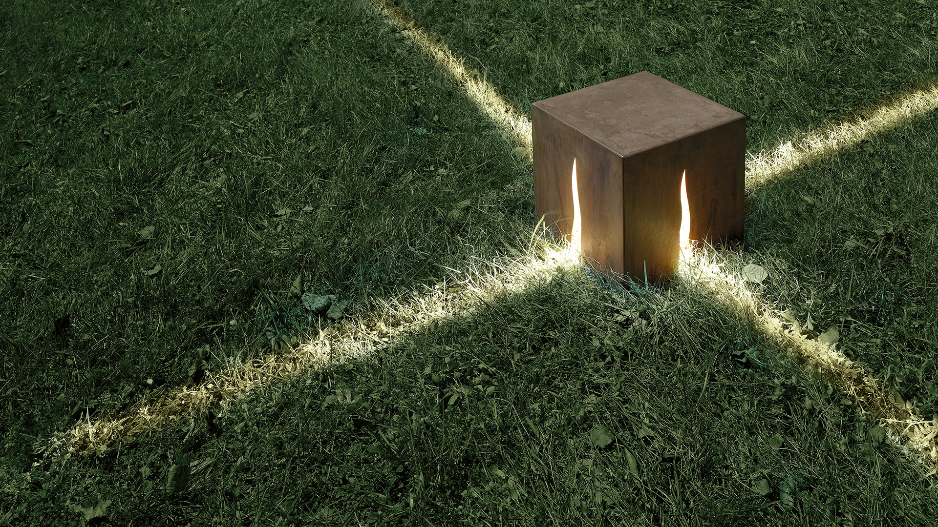 Artemide Granito outdoor cube lamps in dark finish emit warm amber light, placed along a garden path at dusk