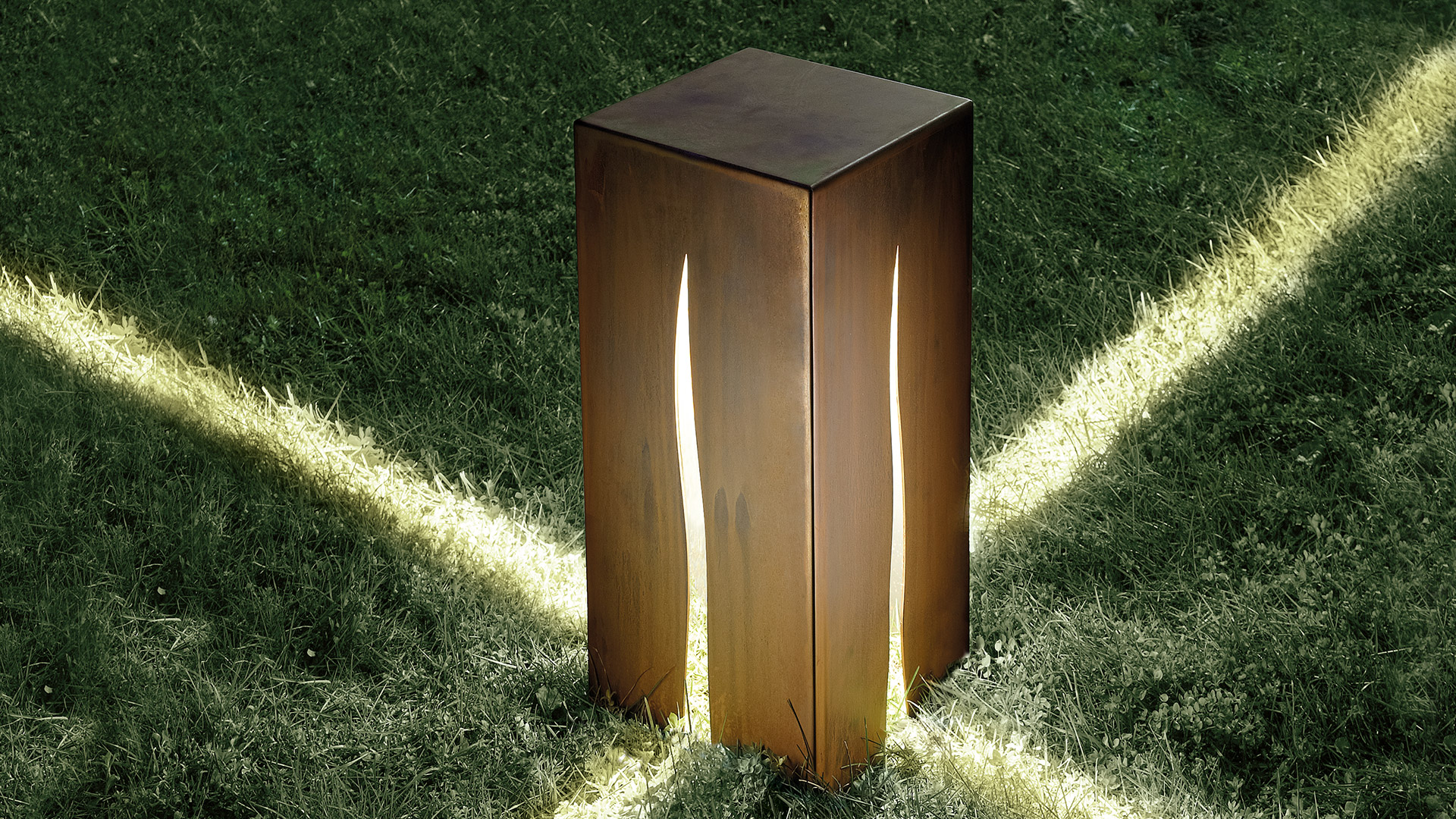 Artemide Granito outdoor ground light: dark corten steel cube with glowing vertical slit, placed on concrete base in garden