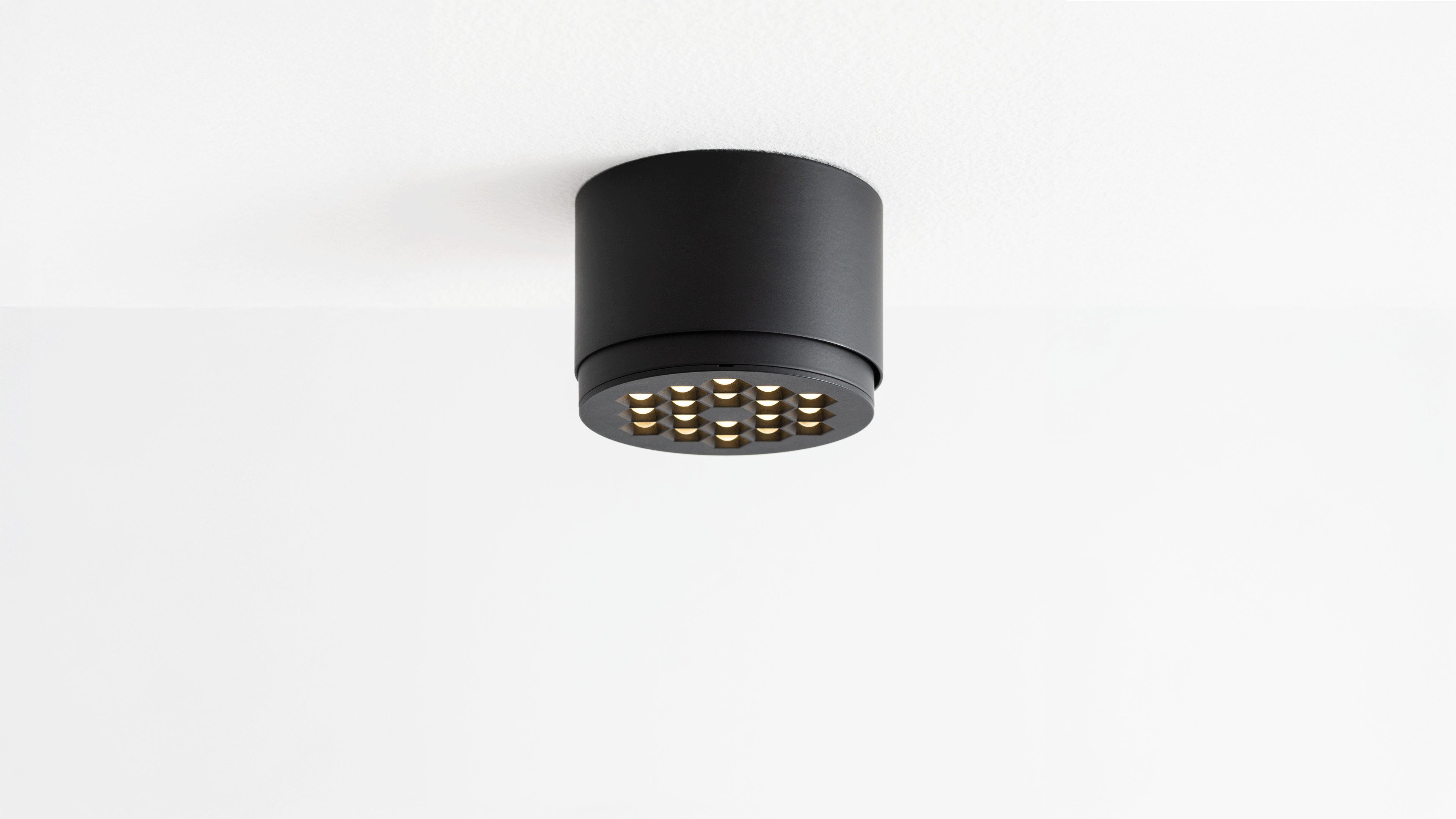 Two Artemide Helgoland LED ceiling lights: left recessed black round fixture, right adjustable blue cylindrical surface-mount with pivoting black head