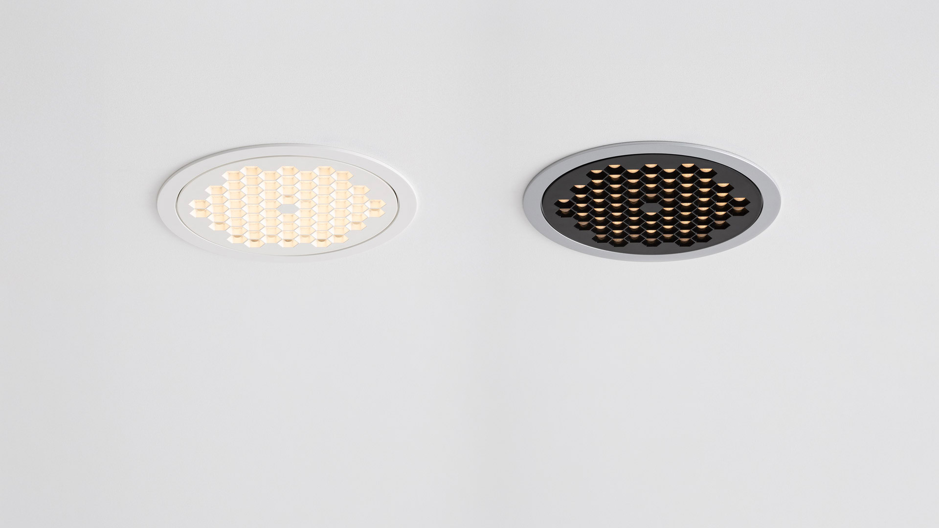 Two Artemide Helgoland recessed LED ceiling lights: left white trim illuminated, right dark trim with honeycomb grid, off