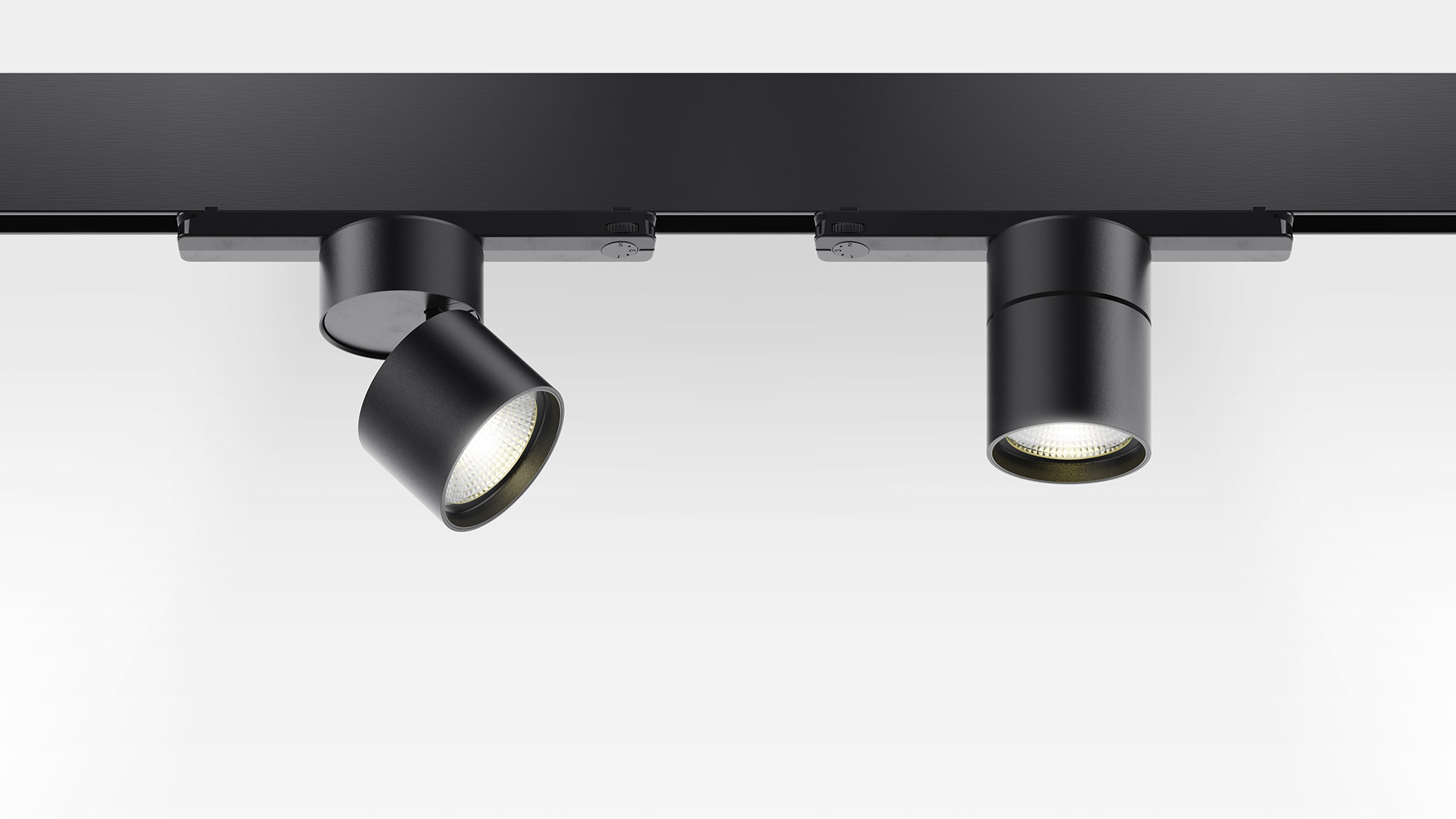 Two black Artemide Hoy Spot track lights mounted on a 3-phase rail, with adjustable cylindrical heads and warm LED light