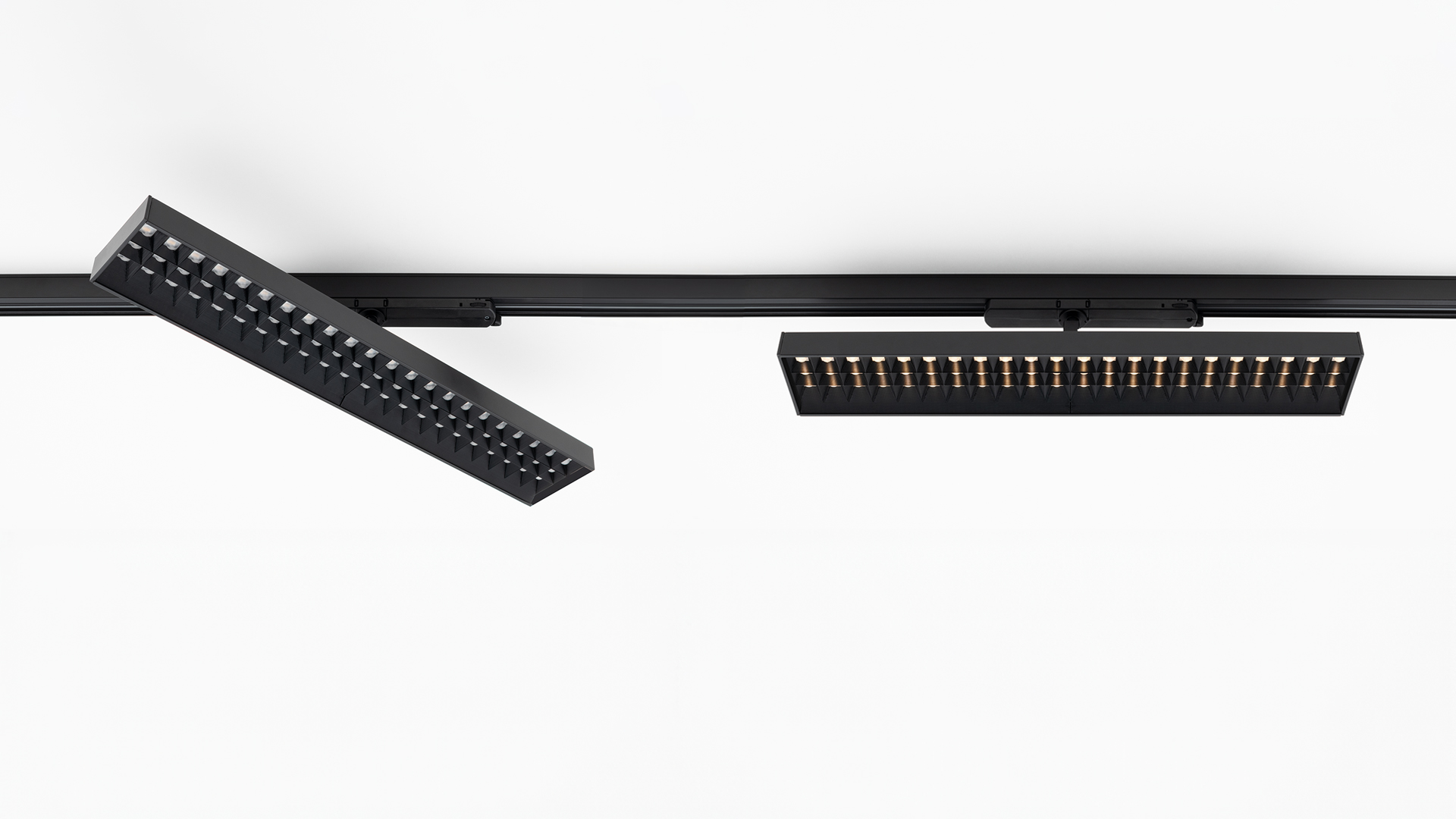 Two Artemide Hoy Refractive 3-Phase Track black LED fixtures on rail: left angled, right horizontal, showing gold LED array