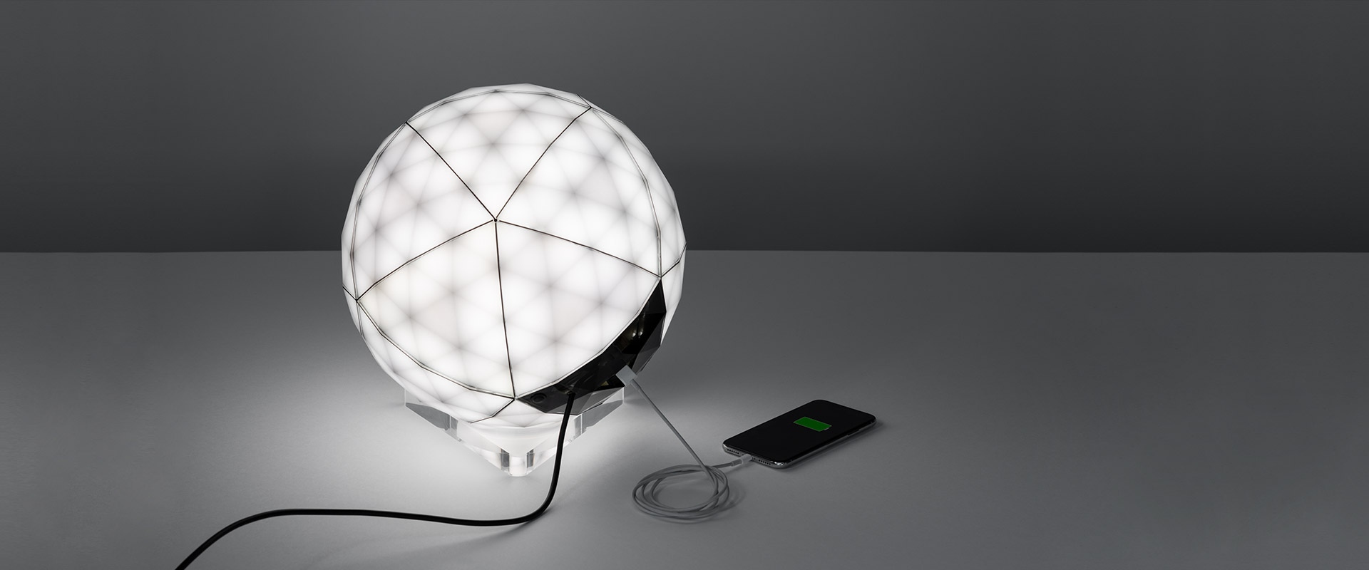 Artemide Huara lamp: faceted spherical diffuser with black and transparent crystal-like surfaces on a clear acrylic base
