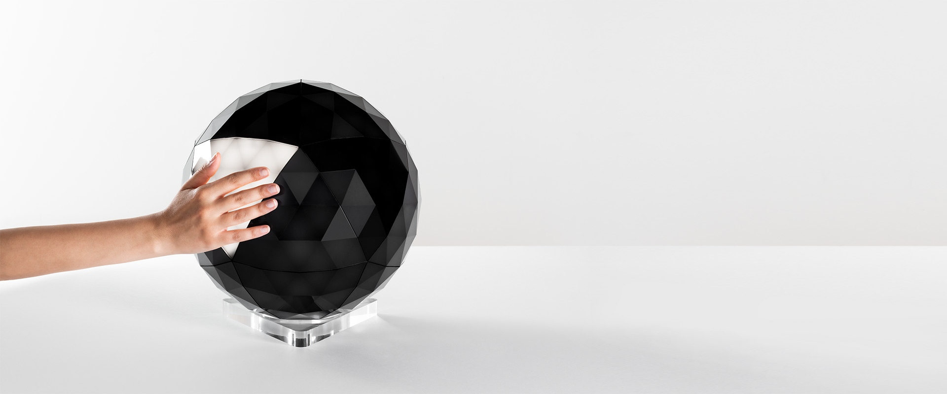 Artemide Huara lamp: spherical geodesic diffuser with geometric wire frame structure on a transparent base, soft glowing light