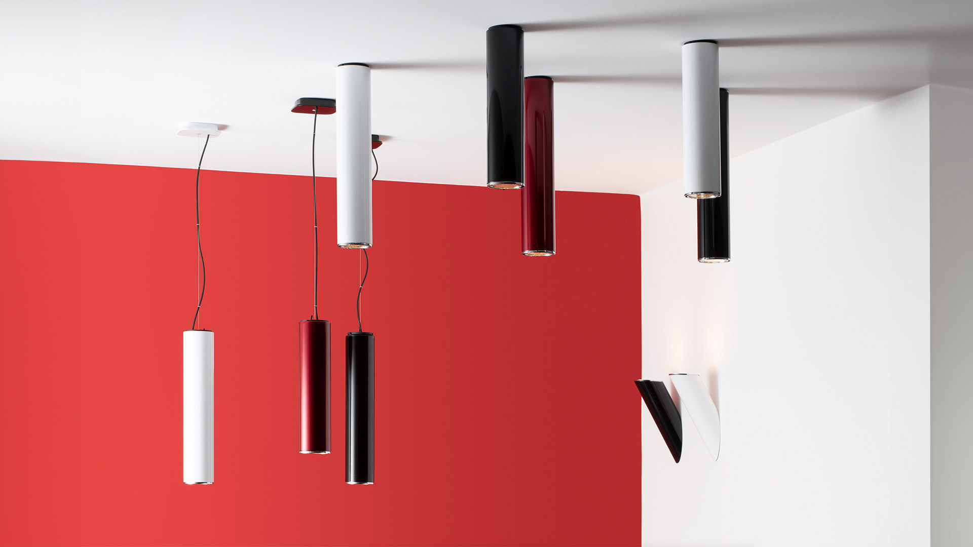 Artemide Ilio wall lamps: two curved blade-shaped sconces, one white emitting light, one black, mounted on a white wall