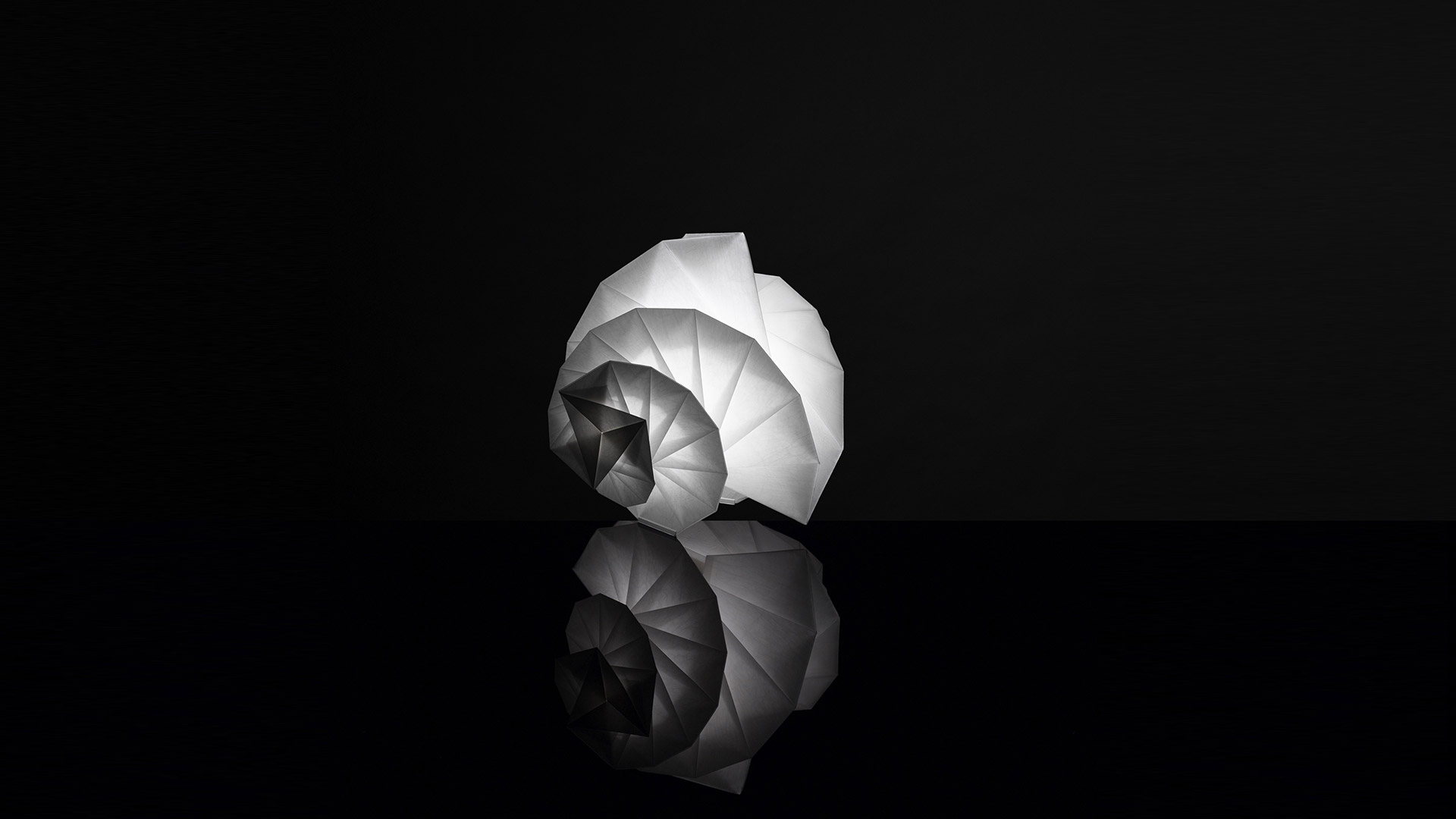 Artemide In-Ei Mendori by Issey Miyake: origami-inspired white folded diffuser in spiral shell shape, reflected on glossy black surface