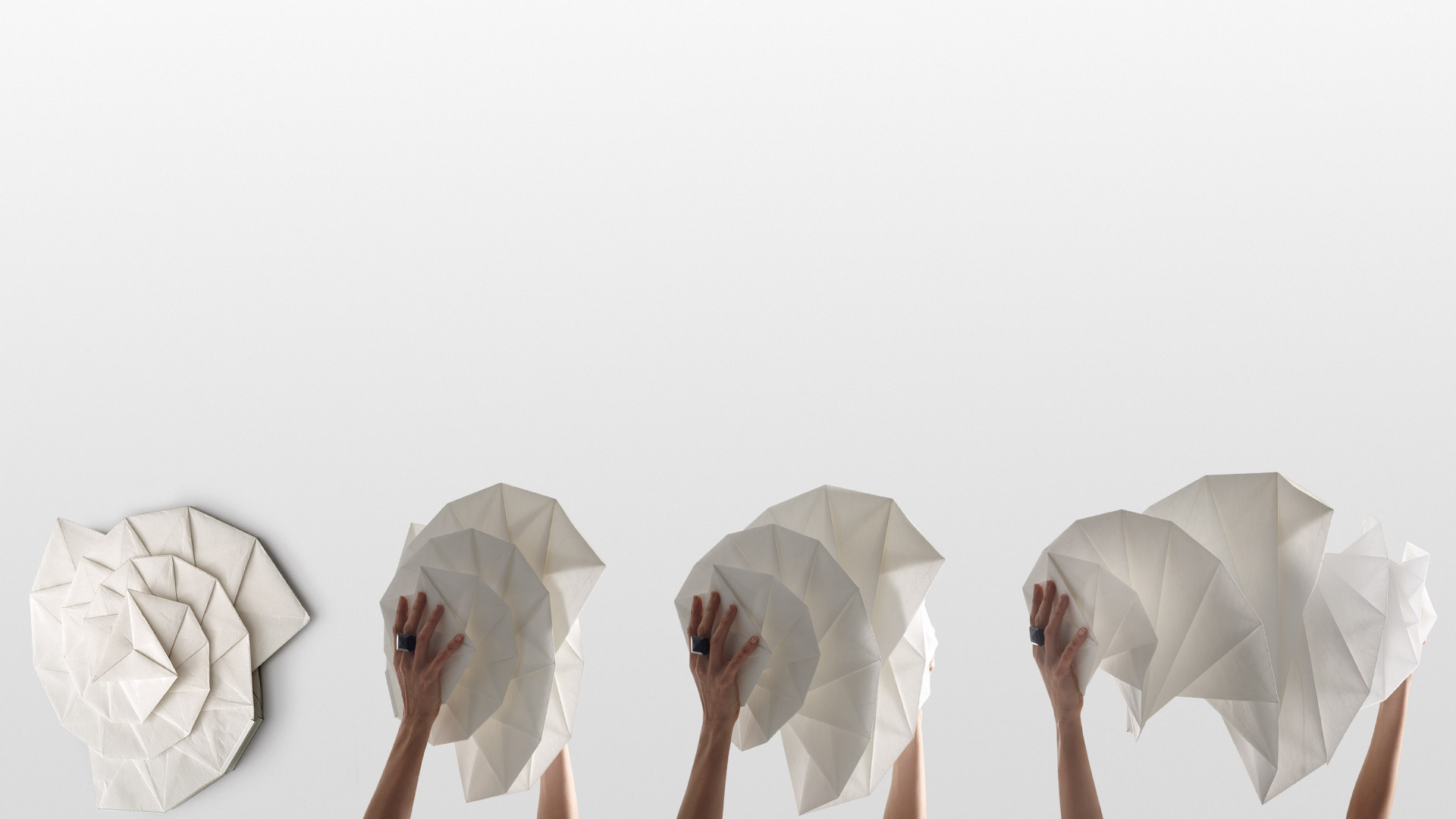 Artemide In-Ei Mendori by Issey Miyake: sequence showing hands shaping white origami-folded paper lampshades into different forms