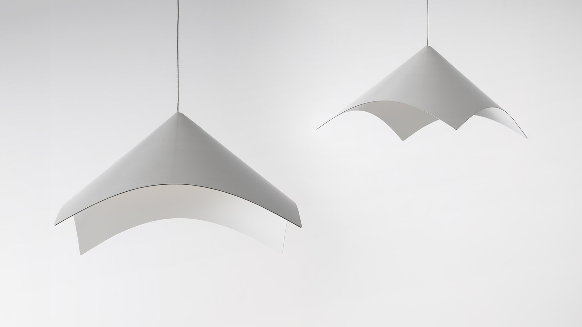 Close-up of Artemide Iperbole lamp's curved brushed aluminum reflector, showcasing its elegant arc and smooth metallic finish