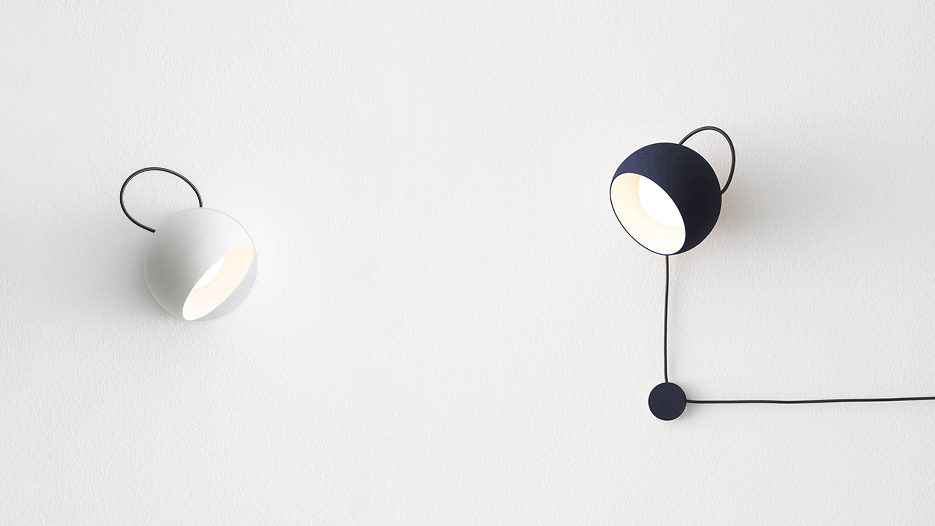 Minimalist dining room with three Artemide Ixa pendant lamps in gold over a wooden table with black chairs