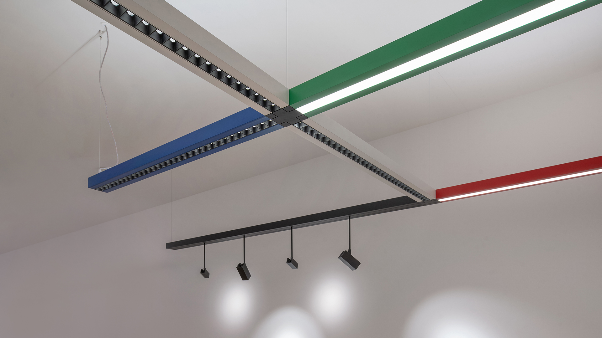 Artemide Katà Métron black modular track lighting system with spotlights and pendants, illuminating dark ceramic sculptures in a gallery setting