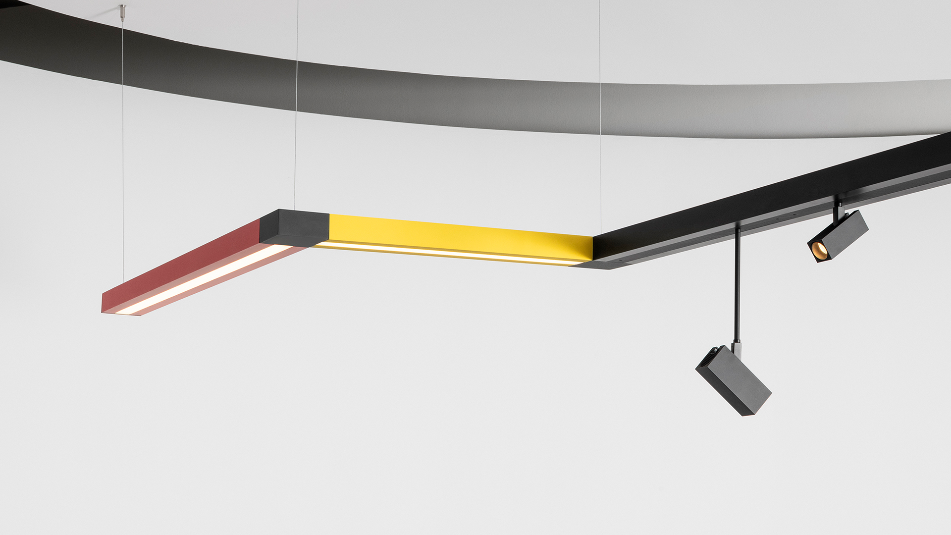 Artemide Katà Métron ceiling installation with black track spotlights, colorful linear LED elements in red, green, blue, and a white panel