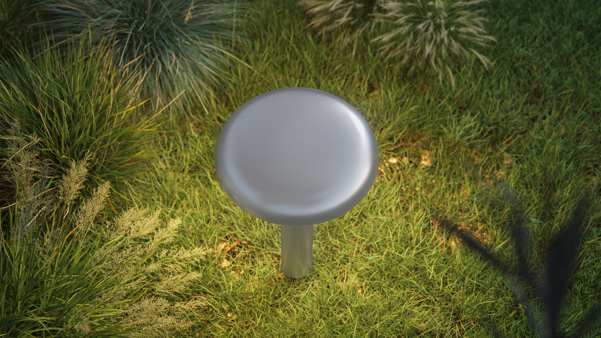 Artemide Knop outdoor lamp: mushroom-shaped fixture with dark disc shade on slim stem, placed among dark gravel near tropical plant