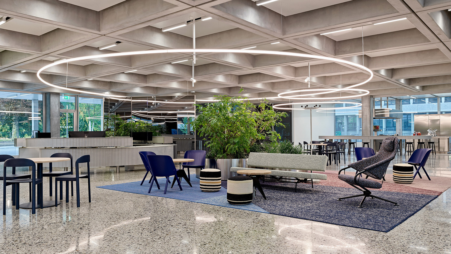 Artemide La Linea circular LED pendant lamp suspended outdoors at night, illuminating a classical courtyard with columns and potted plants