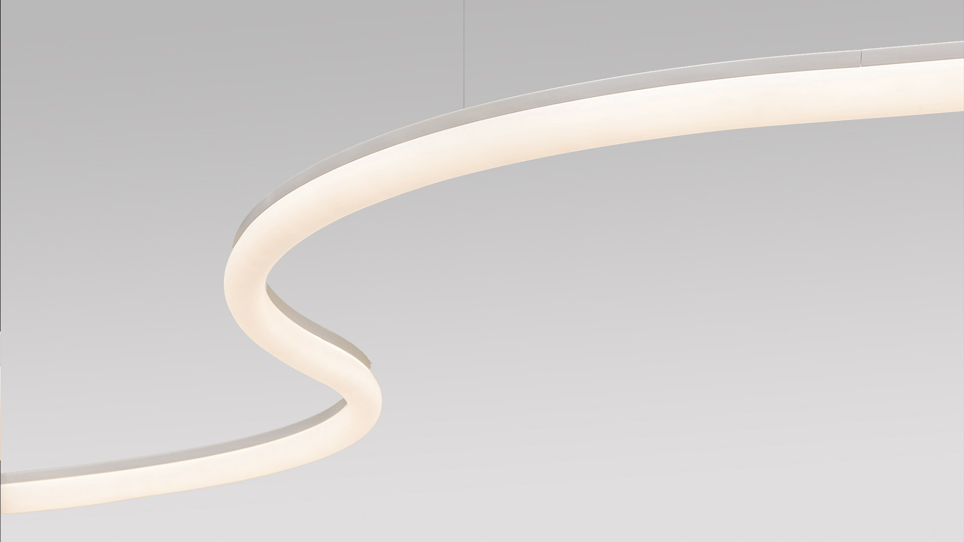 Two Artemide La Linea BIG cylindrical luminaires with opal white diffusers, emitting soft warm light, displayed on a white surface