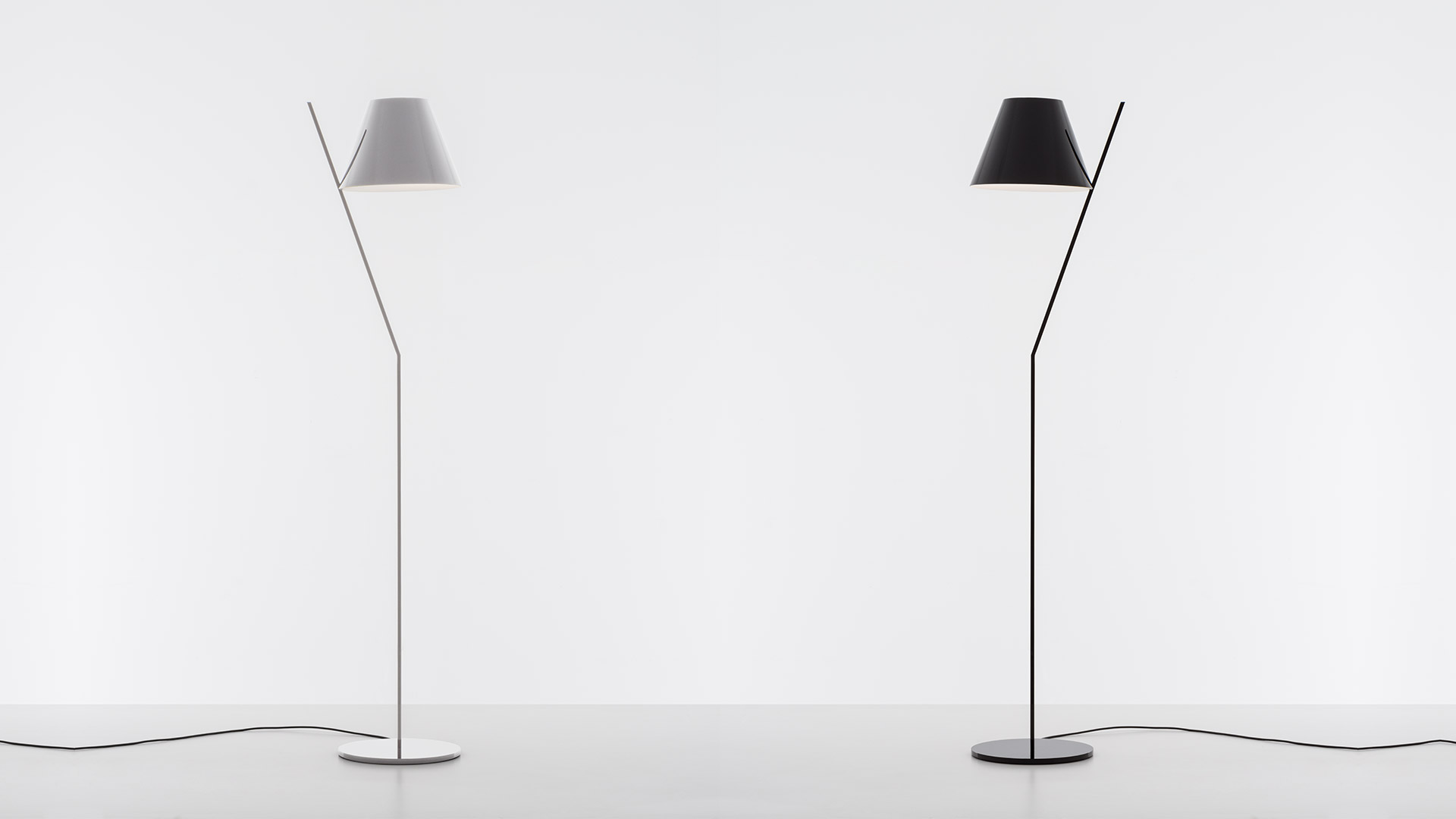 Two La Petite Floor lamps by Artemide: left white version, right black version, both with conical shade on slim angled stem