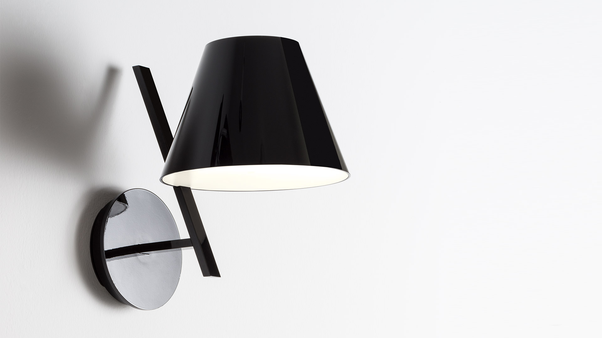 Artemide La Petite Wall lamp: glossy black conical shade on angled chrome arm mounted on circular wall plate
