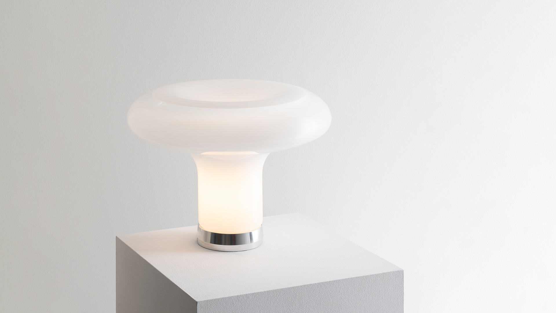 Artemide Lesbo table lamp with white opal glass mushroom shade on a white outdoor terrace table with stone balustrade