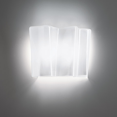 Artemide Logico wall lamp with layered frosted glass diffuser emitting soft white light against a grey wall