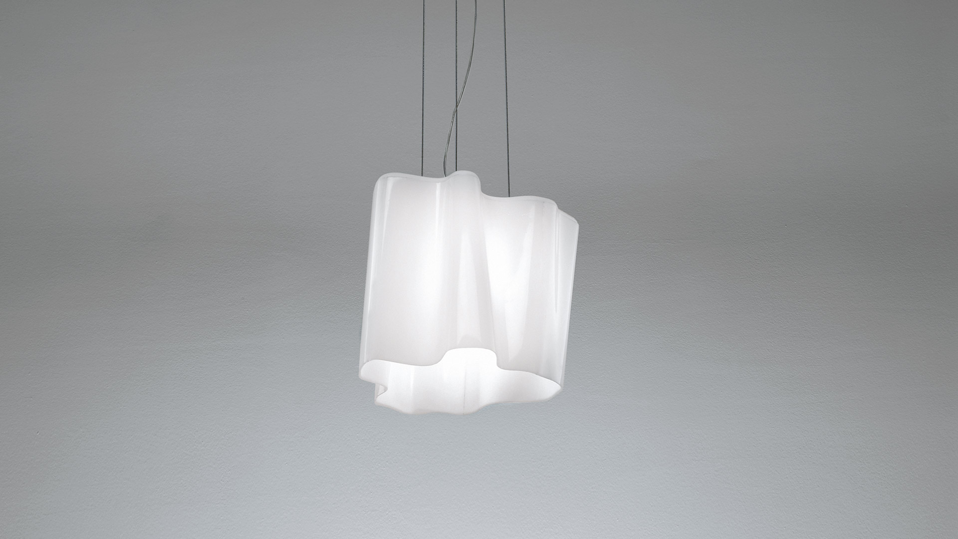 Artemide Logico pendant lamp with white opal diffuser in an irregular geometric shape, suspended by thin cables from ceiling