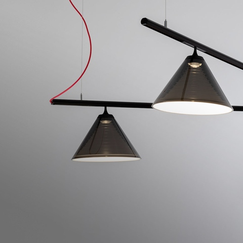 Artemide Look at Me System: black horizontal bar with two smoked conical pendant shades, one illuminated, suspended by red and grey cables