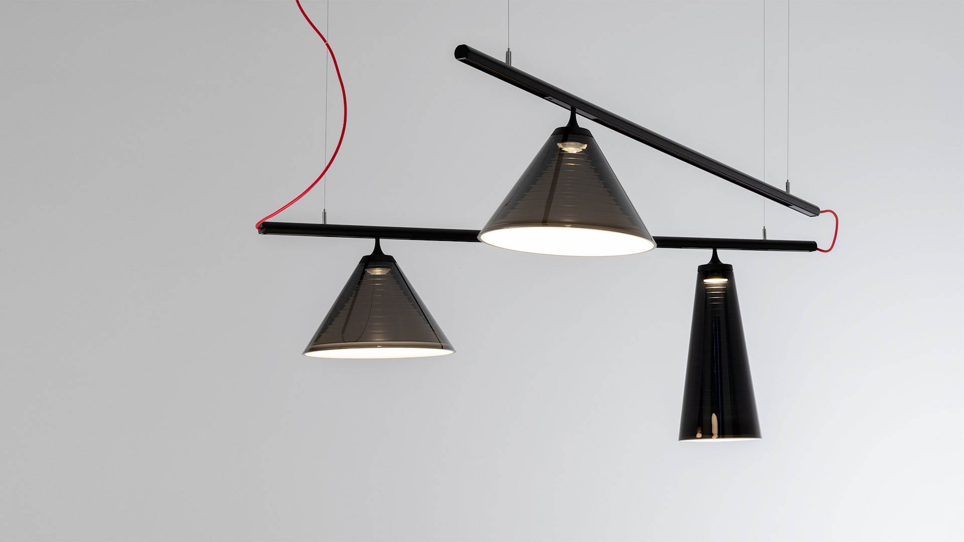 Artemide Look at Me System: three conical pendant lamps in dark finish suspended from a black horizontal bar with red cable