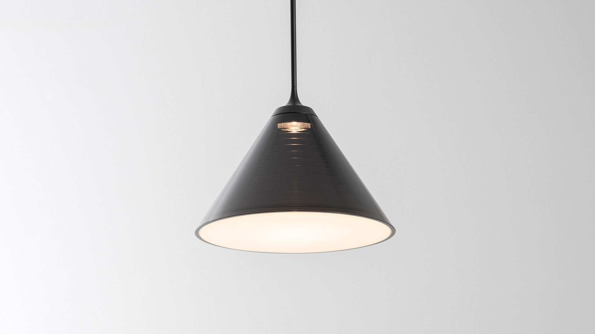 Two groups of Artemide Look at Me pendant lamps with dark conical shades hanging from ceiling roses against a dark background