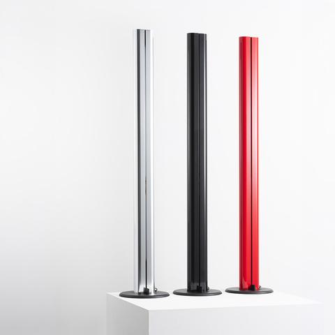 Three Artemide Megaron floor lamps in chrome, black, and red, featuring slim cylindrical columns on round bases