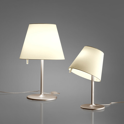 Two Artemide Melampo Tavolo table lamps on aluminum bases: left upright with white conical shade, right tilted at an angle