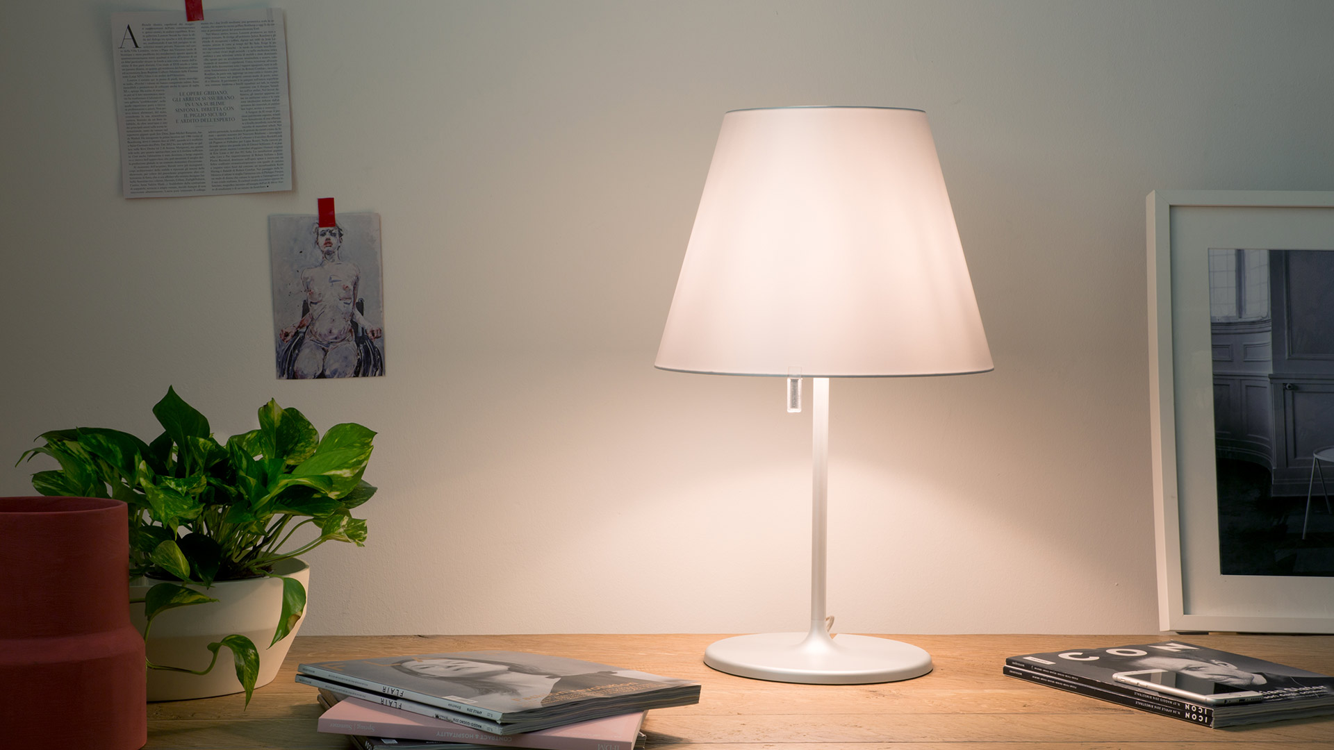 Four Artemide Melampo Tavolo table lamps with conical shades in white and beige, shown in various sizes and tilted positions on slim stems