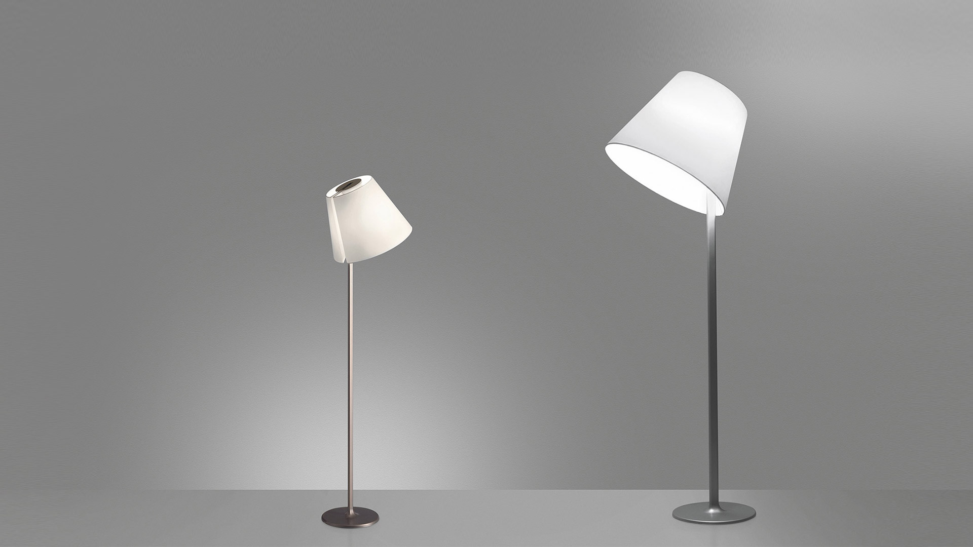 Two Artemide Melampo Terra floor lamps with tilting white conical shades on slender metal poles, shown in small and large sizes