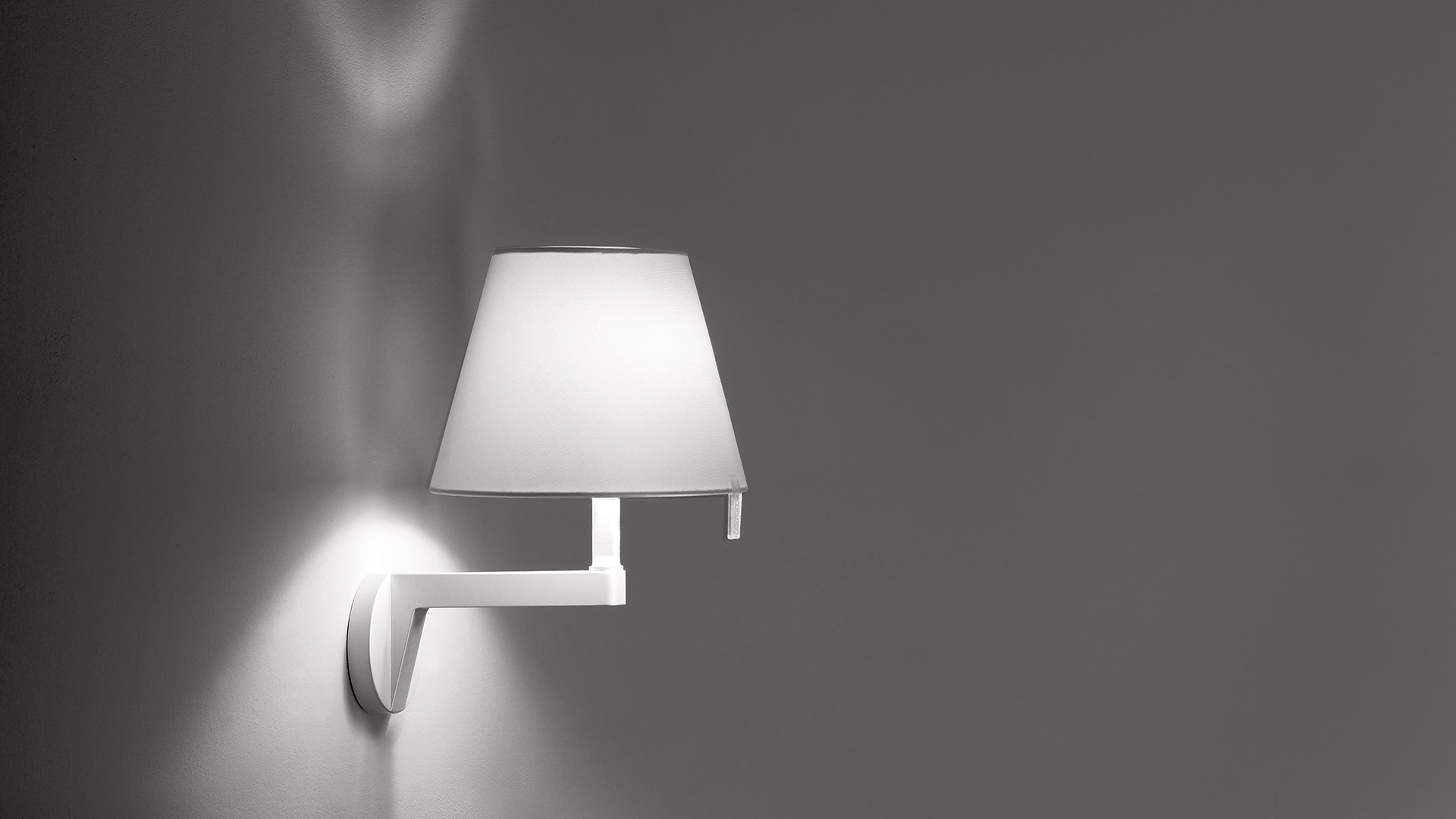 Artemide Melampo Parete wall lamp with white conical shade on adjustable aluminum arm, casting upward light on wall