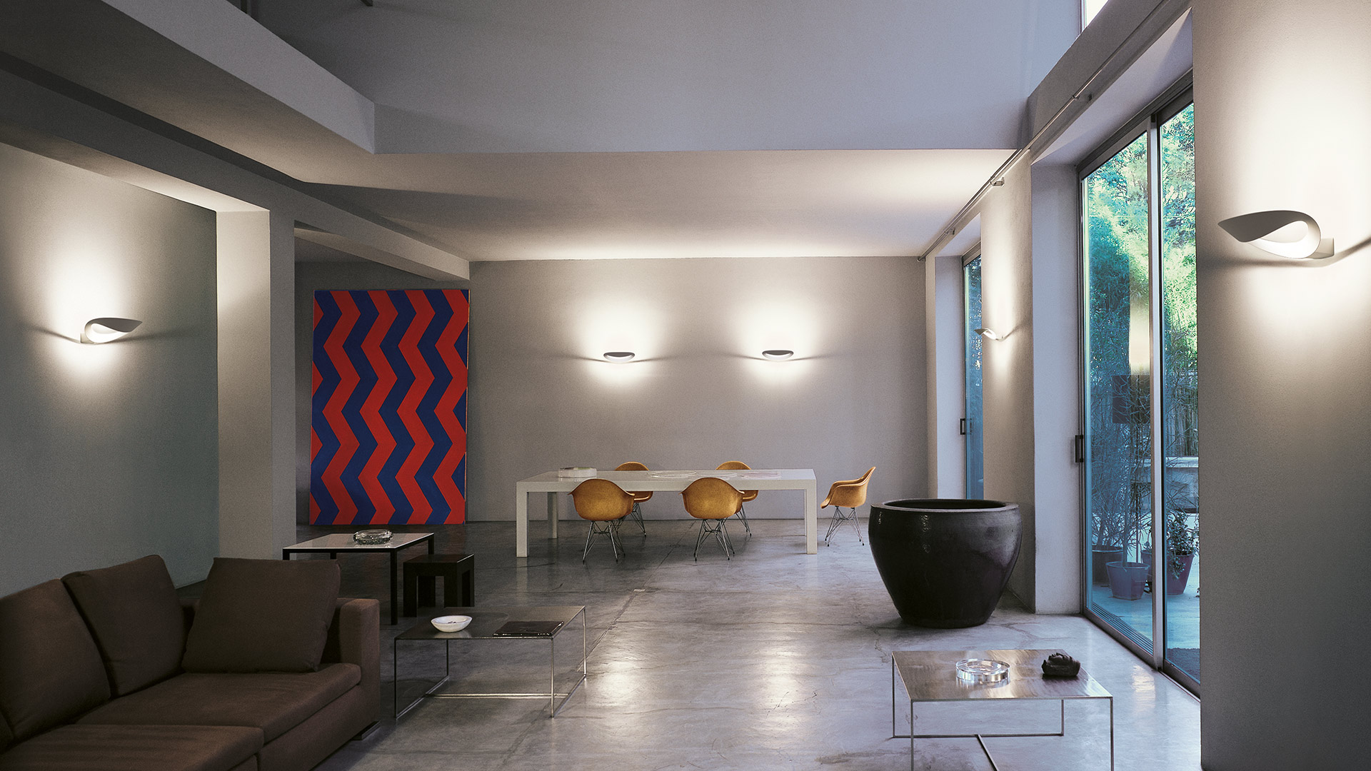 Artemide Mesmeri wall lamp in polished chrome, featuring a fluid sculptural ribbon-like form mounted on a white wall