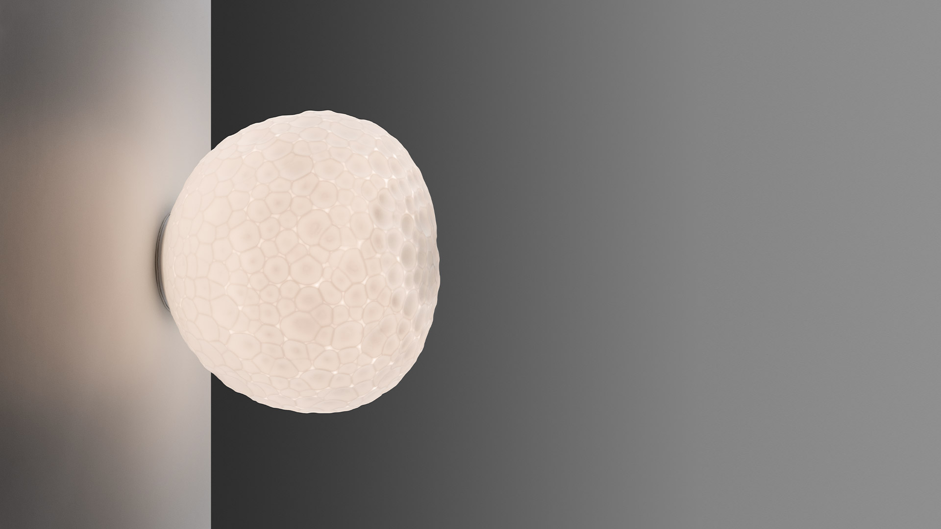 Artemide Meteorite wall/ceiling lamp: spherical white diffuser with moon-like crater texture, mounted on a wall corner