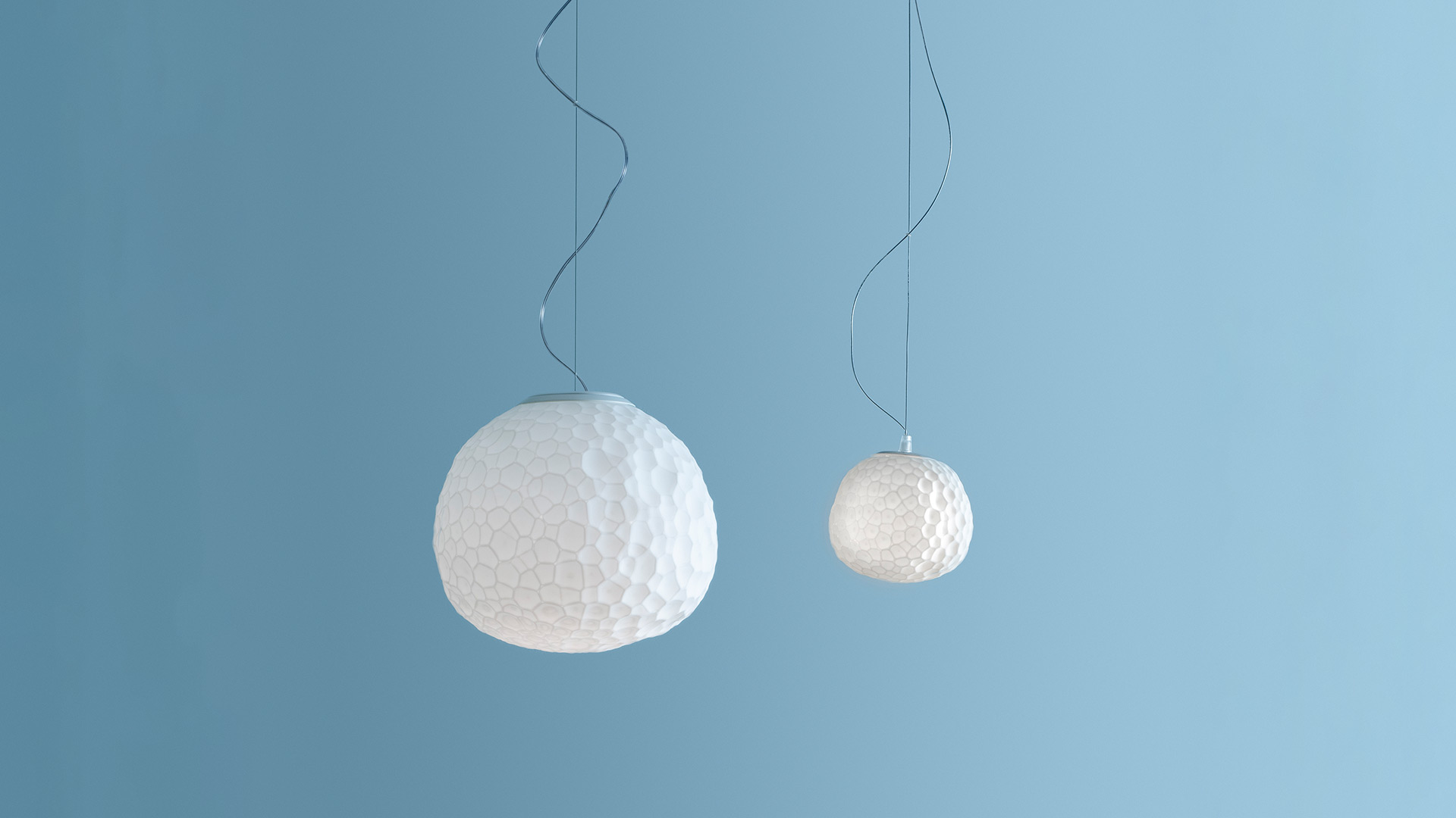 Artemide Meteorite pendant lamp: opal white spherical diffuser with organic cellular texture, suspended by a dark cable