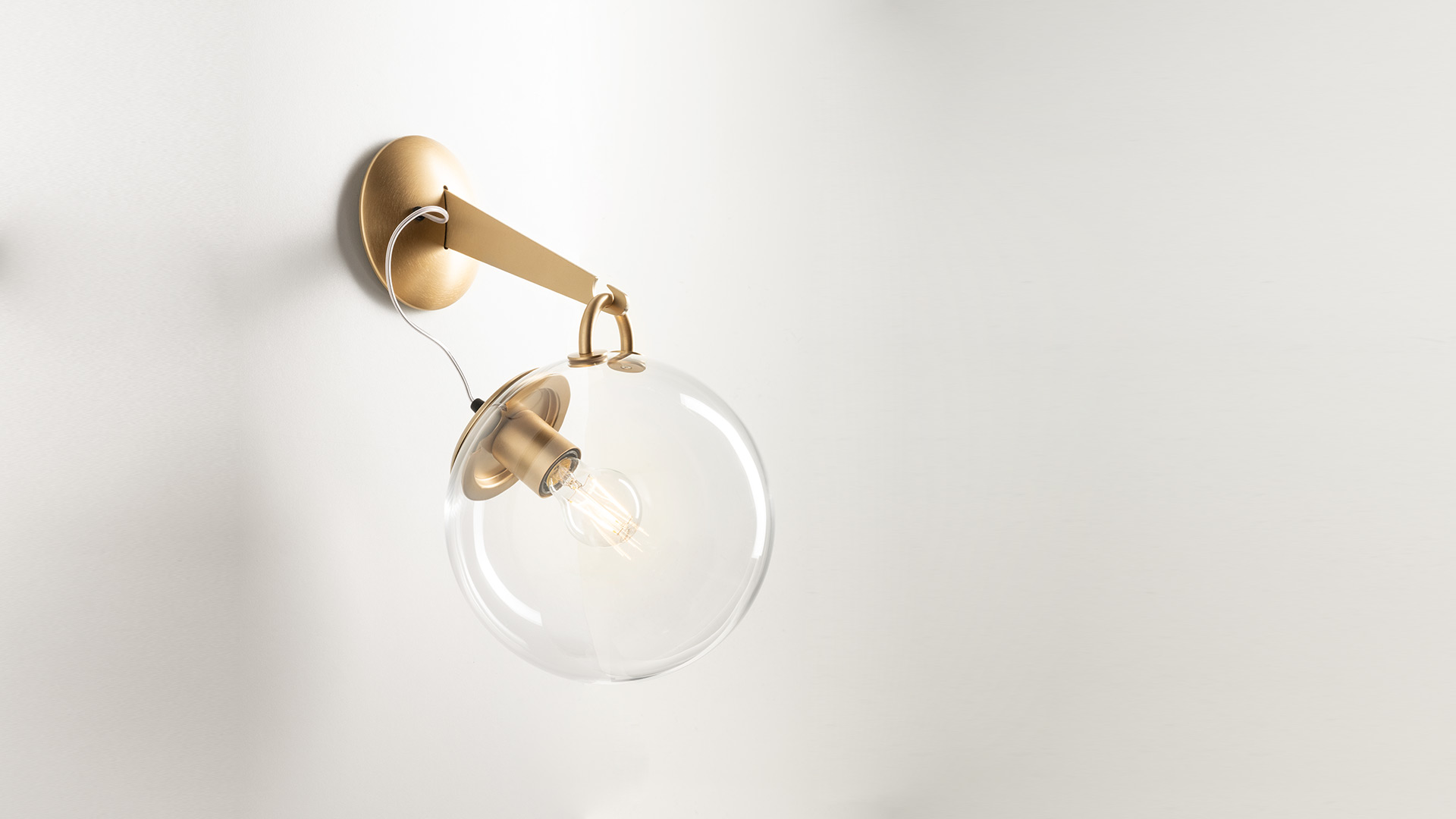Two Artemide Miconos pendant lamps: clear glass spheres with brass fittings, shown off and on, suspended by thin cables