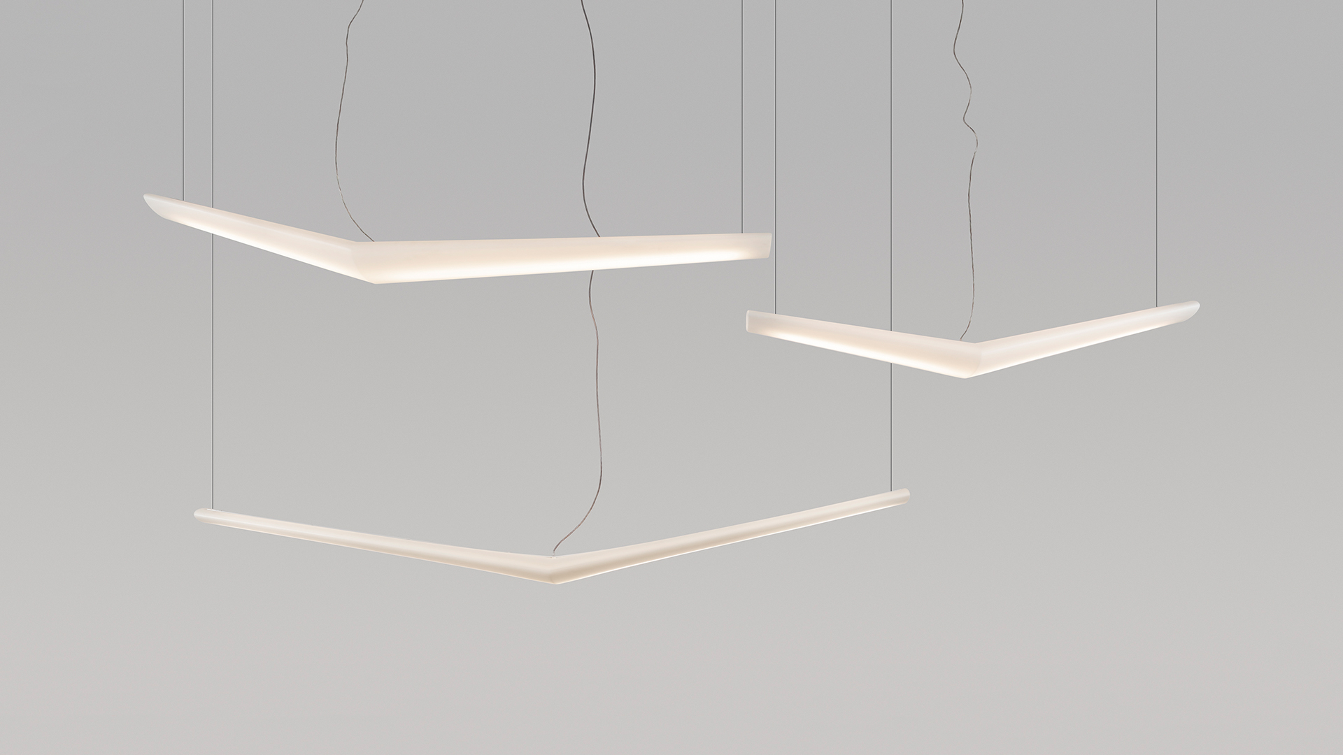 Three Artemide Mouette pendant lamps with angular boomerang-shaped white LED profiles suspended by thin cables