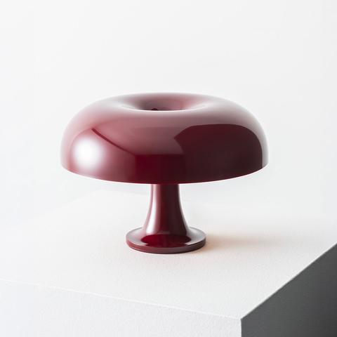 Artemide Nessino table lamp in burgundy red, featuring a glossy donut-shaped shade on a pedestal base