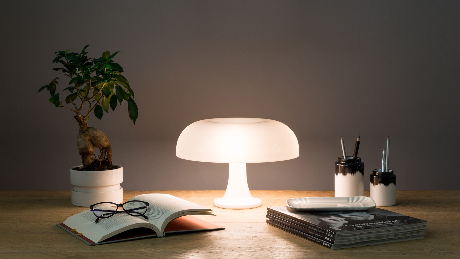 Eight Artemide Nessino table lamps in a row, showcasing the full color range: orange, red, yellow, black, white, blue, light blue, and green